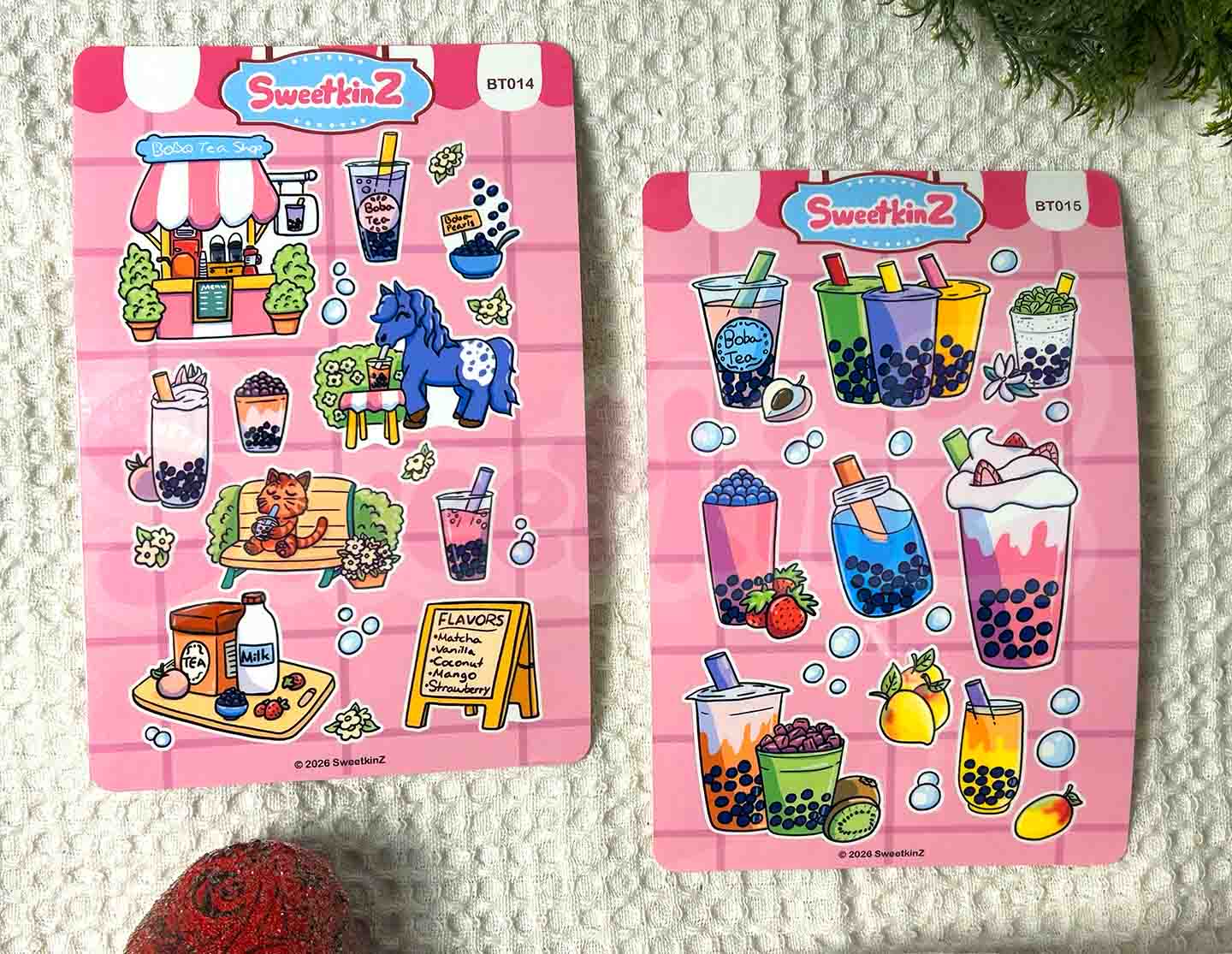 Two pink sticker sheets with boba tea themed items on them on a textured background.