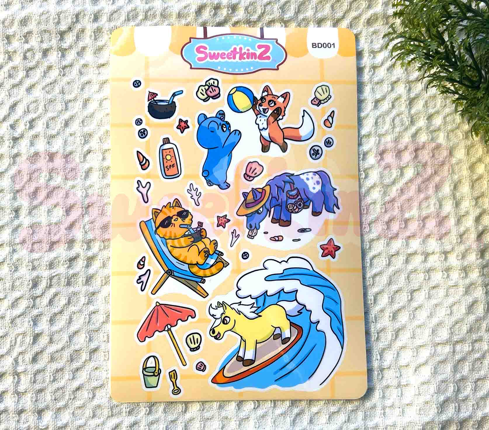 Sheet of colorful animal and beach objects stickers on a textured surface with 'SweetkinZ' branding.