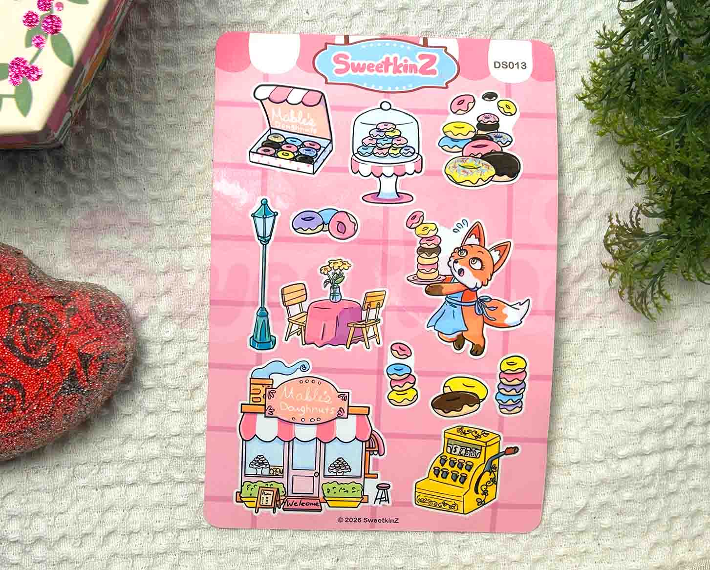 Sticker sheet with cartoon characters, a doughnut shop, and doughnuts on a textured surface