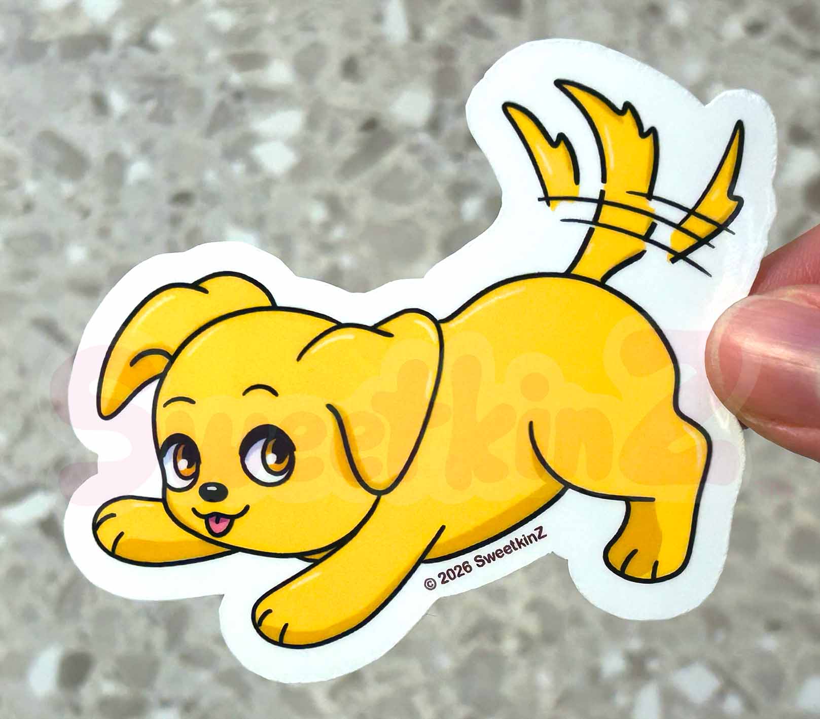Cartoon dog sticker held by a hand on a textured surface