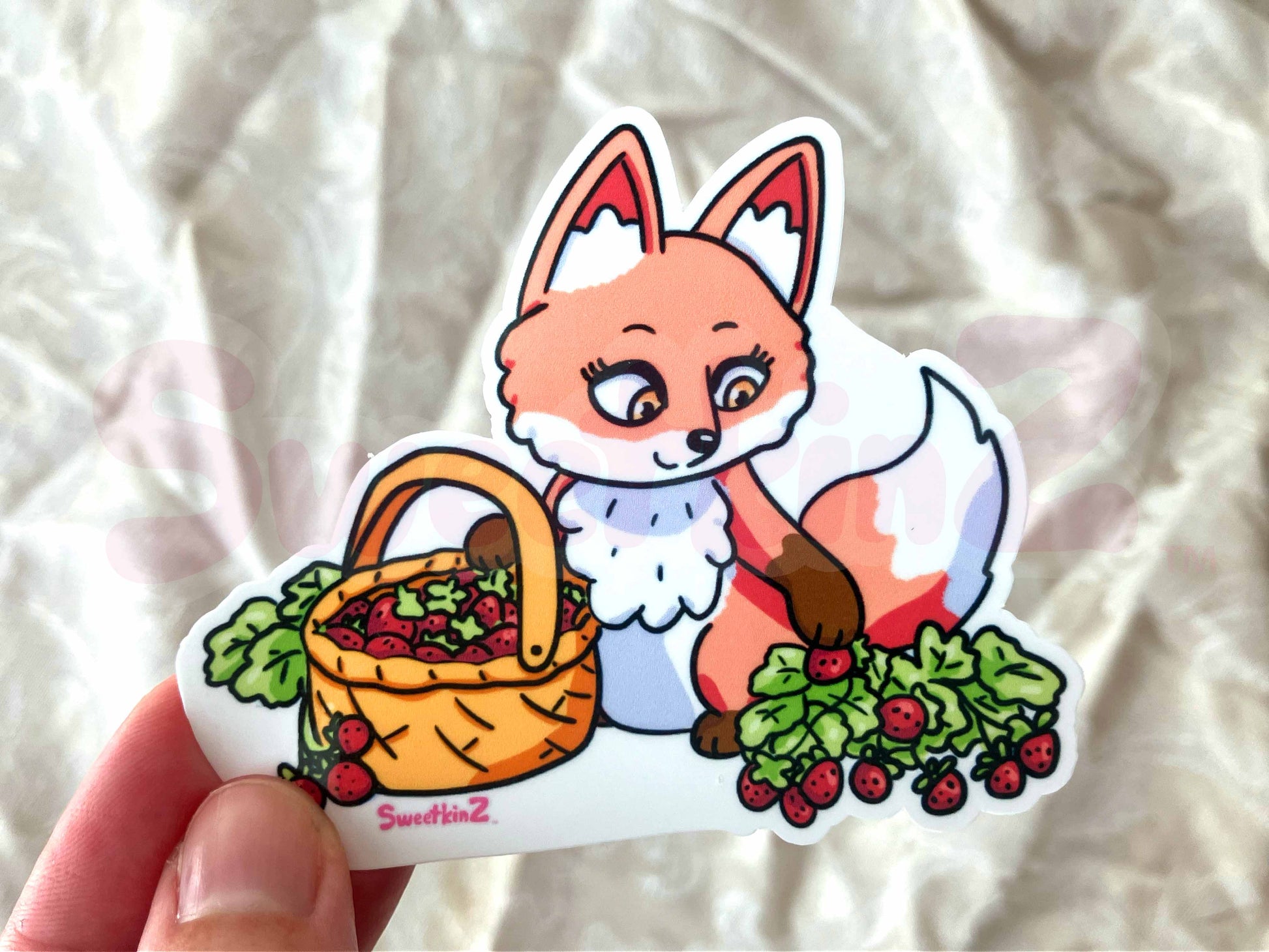 Sticker of a fox with a basket of berries held by a hand against a textured white background