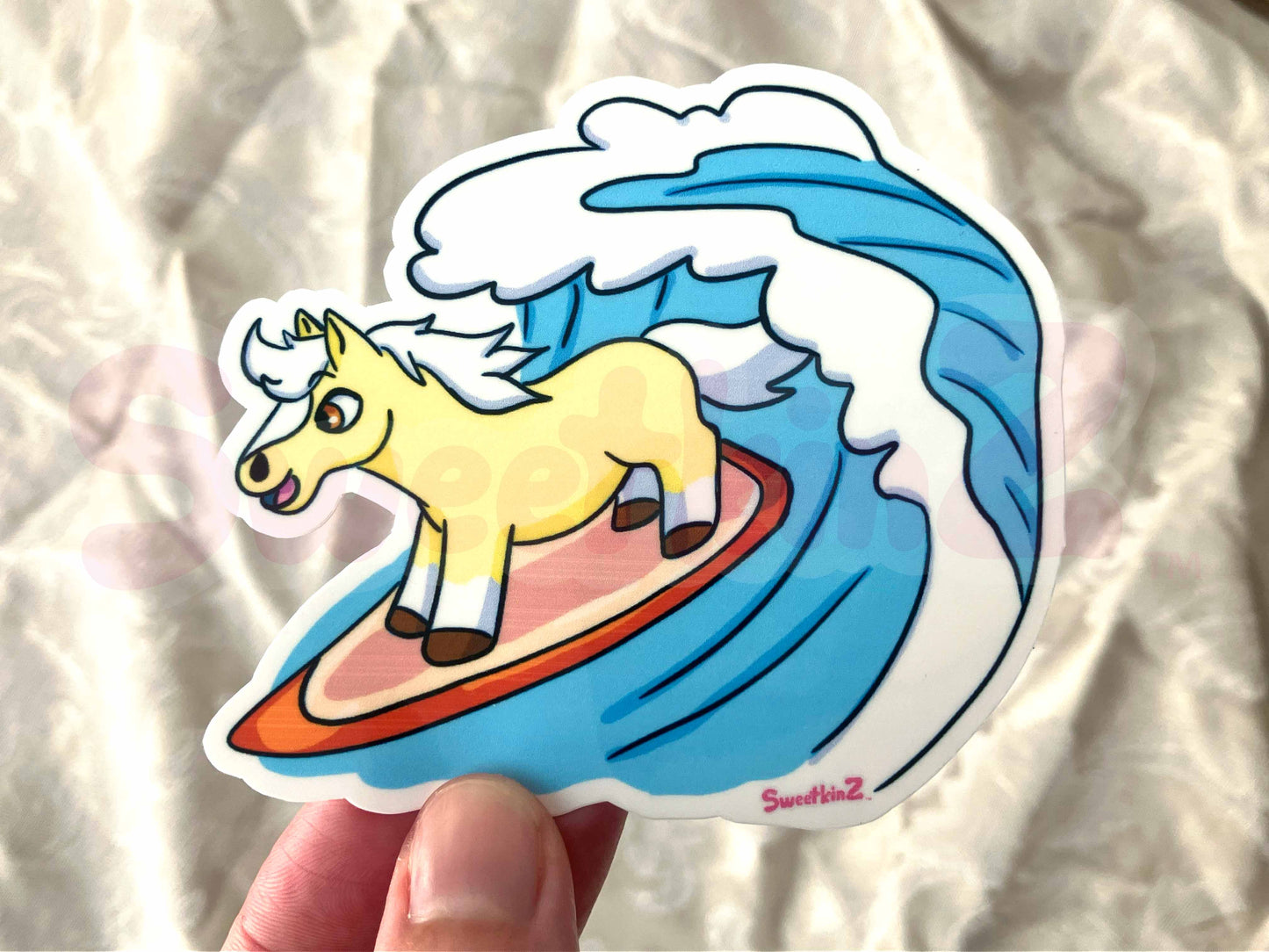 Sticker of a horse on a surfboard with a wave design, held against a neutral background.