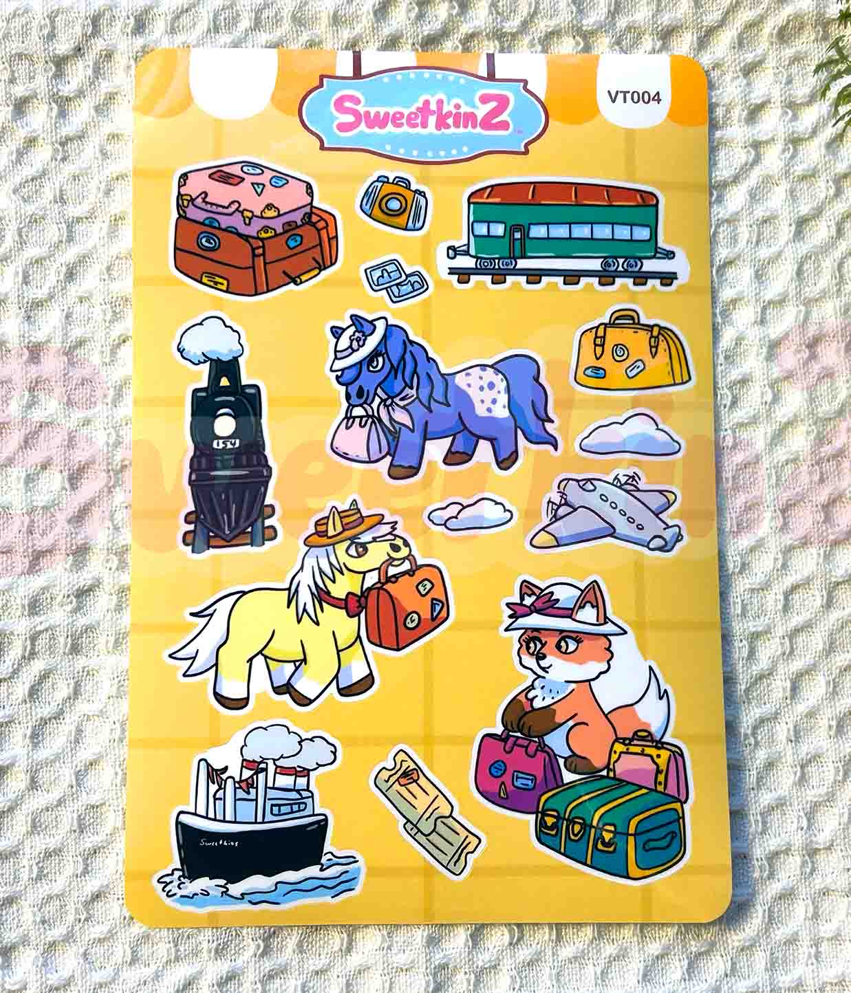 Sticker sheet with cartoon animals and travel-themed items on a yellow background, featuring the brand 'SweetkinZ'.